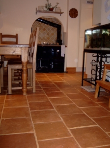 A kitchen floor laid with terracotta tiles